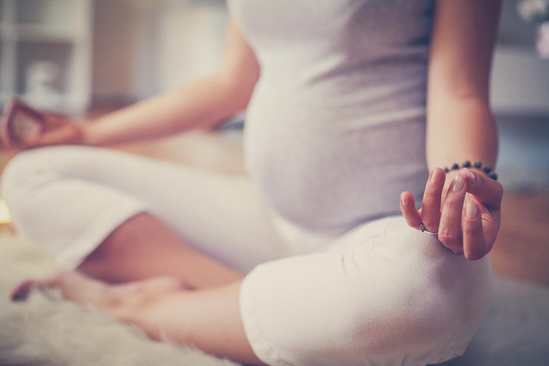 Bilde av gravid dame som sitter i yogastilling. Foto: AdobeStock